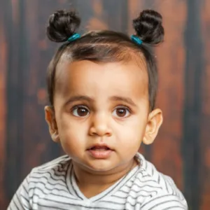 Charming Indian baby boy with top knots hairstyl